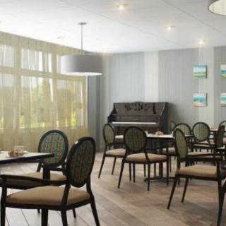 A cozy dining area with elegant chairs and tables, featuring a piano against the wall.