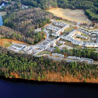 Aerial view of a residential area surrounded by forest and near a lake.