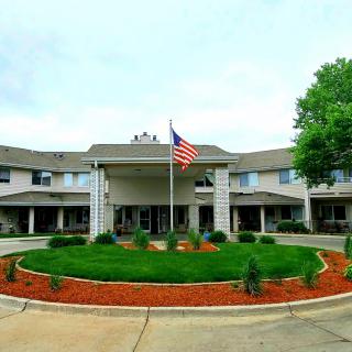 A symmetrical building with a circular driveway and an American flag at the entrance.