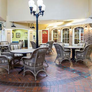 An inviting indoor dining area with wicker furniture and brick flooring, illuminated by decorative lamps.