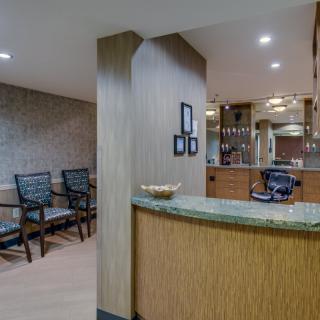 A modern office reception area featuring a counter and waiting chairs.