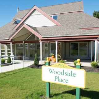 A view of a residential building with a sign that reads 'Woodside Place' in the front.