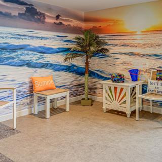 Cozy indoor seating area with a beach-themed mural and tropical decor.