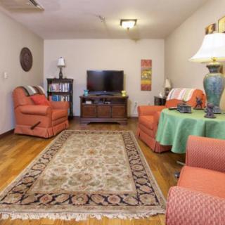 A cozy living room with warm-colored furniture, a patterned rug, and a television.