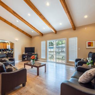 Modern living room with wood beam ceiling, ample natural light, and contemporary furnishings.