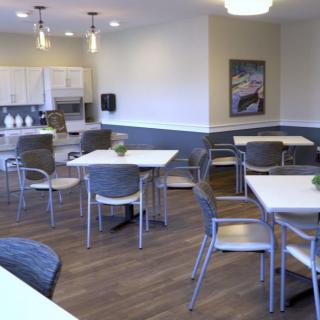 A modern dining area with tables and chairs, adjacent to a kitchen space.