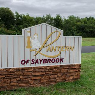 A welcoming sign for the Lantern of Saybrook, set against a green landscape.