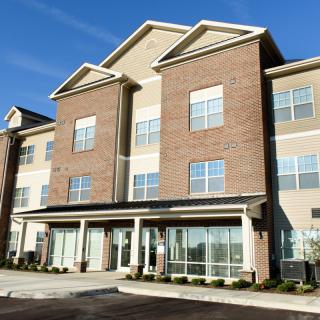 A modern brick apartment building with large windows under a clear blue sky.