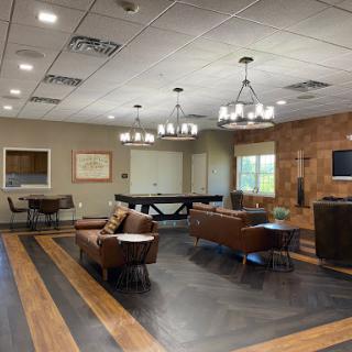 A stylish lounge area featuring comfortable seating, a pool table, and elegant chandeliers.