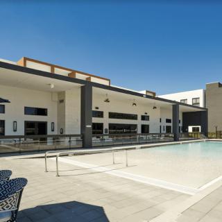 A modern outdoor swimming pool area with contemporary architecture and a sunny ambiance.