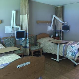 A view of a modern hospital patient room featuring two beds and medical equipment.