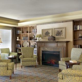 A cozy living room with a fireplace, armchairs, and bookshelves creating a warm atmosphere.