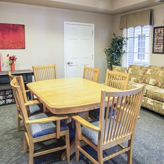 A cozy dining area with a wooden table and matching chairs, complemented by a sofa and decorative elements.