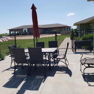 Outdoor patio area with furniture including a table, chairs, and an umbrella under a clear sky.