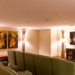A cozy home theater with green seating, wall art, and ambient lighting.