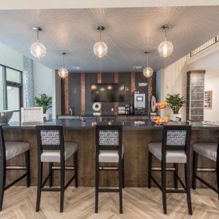 A modern kitchen with a sleek bar counter and stylish pendant lighting.