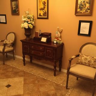 A cozy waiting room with elegant chairs, a decorative table, and warm lighting.