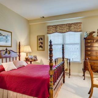 A cozy bedroom with traditional decor, featuring a wooden bed frame and red bedding.