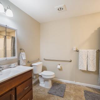 A modern and clean bathroom with a sink, toilet, mirror, and towel rack.