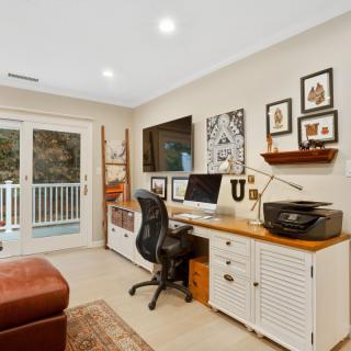A cozy home office setup with a desk, computer, chair, and decorative artwork.