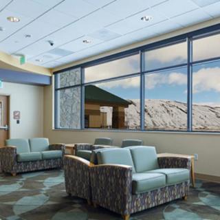 A spacious and well-lit waiting room with comfortable seating and a picturesque mountain view through large windows.