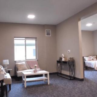 A cozy living room with a sofa and table, adjacent to a bedroom.