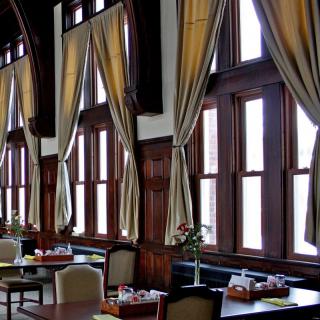 A dining area with elegant curtains and large windows allowing natural light.