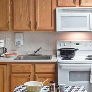 A kitchen with wooden cabinets, a microwave, oven, and a countertop with cooking items.