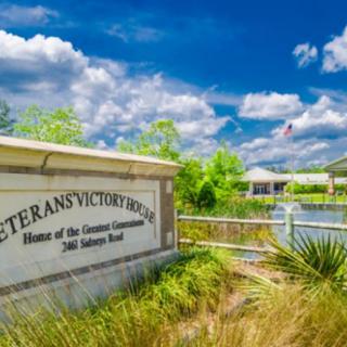 A scenic view of the Veterans Victory House with a clear blue sky and lush surroundings.
