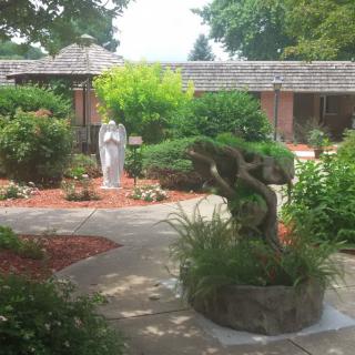 A serene garden with a statue and well-maintained landscaping.