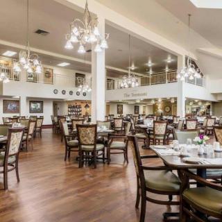 An elegant dining room with neatly arranged tables and chairs, adorned with chandeliers.