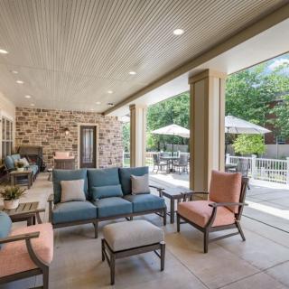 A spacious covered patio featuring comfortable outdoor seating with views of a well-maintained garden.