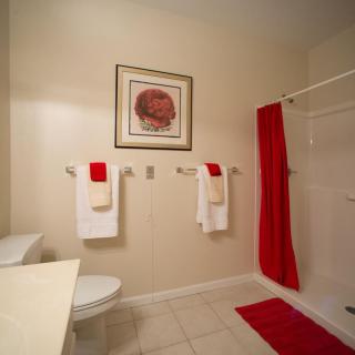 A modern bathroom with red accents, featuring neatly arranged towels and a shower area.