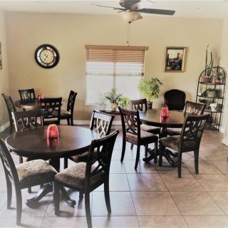 A cozy dining area with multiple round tables and chairs, decorated with wall art and plants.