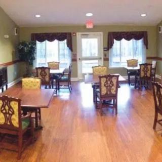 An empty dining room with wooden floors and several tables and chairs.