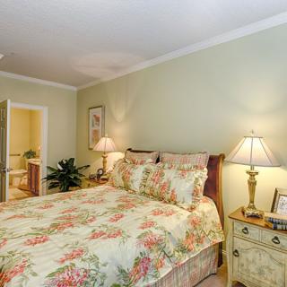 A cozy bedroom featuring floral bedding and warm lighting from table lamps, showcasing a traditional interior design.