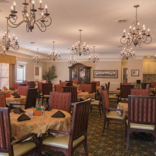 An elegant dining room with chandeliers and neatly arranged tables and chairs.