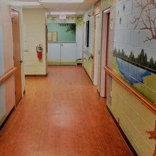 A colorful hospital corridor with murals on the walls.