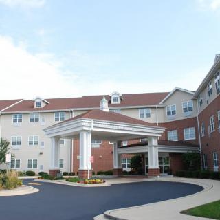 A large, multi-story building with a covered entrance and driveway.