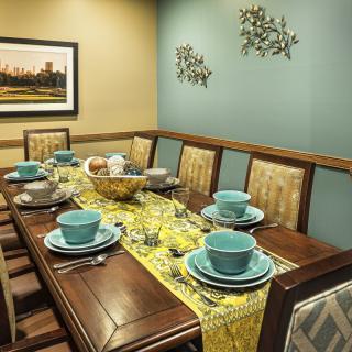 A cozy dining room with a neatly set table featuring turquoise plates and a yellow table runner.