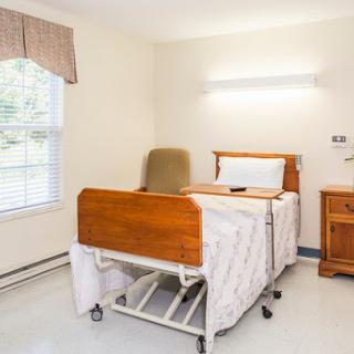 A clean and organized hospital patient room featuring an adjustable bed and natural light.