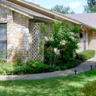 A charming residential house with stone features, surrounded by vibrant landscaping.