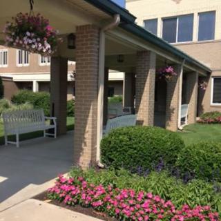 A landscaped garden area with flowers and a bench in front of a building.