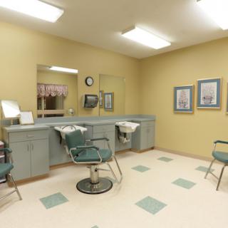 A tidy and well-lit barber shop with green chairs and a minimalist design.