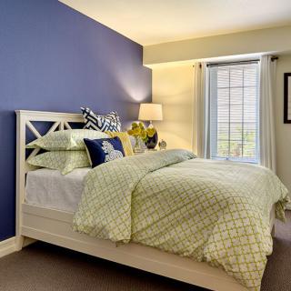 A cozy bedroom with a blue accent wall, neatly made bed, and soft lighting.