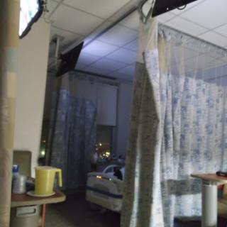 A view of a patient room in a hospital with curtains separating different areas.