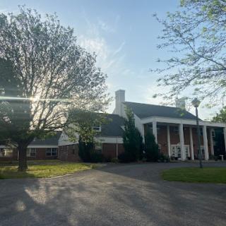 A picturesque view of a well-designed building surrounded by trees, bathed in sunlight.