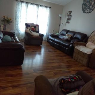 A cozy living room with sofas and recliners on a hardwood floor.