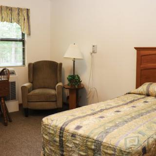 A cozy bedroom with a single bed and armchair near the window.