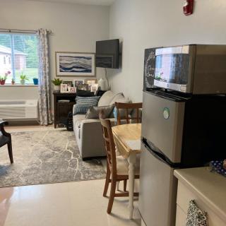 A cozy living space with a fridge, dining table, and comfortable seating area.